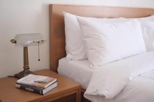 Cama con almohadas blancas y mesa con lámpara en Aginana Villas, en san juan la union