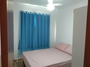 um quarto com uma cama e uma cortina azul em Apartamento 3/4, 1 suíte Vog Atlântico em Ilhéus