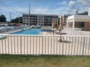 una valla blanca alrededor de una piscina con mesa y sombrilla en Apartamento 3/4, 1 suíte Vog Atlântico en Ilhéus
