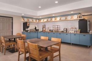 a kitchen with blue cabinets and wooden tables and chairs at Country Inn & Suites by Radisson, Detroit Lakes, MN in Detroit Lakes