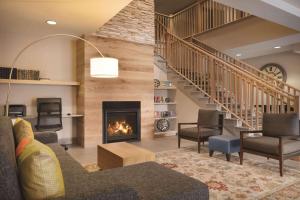 a living room with a fireplace and a staircase at Country Inn & Suites by Radisson, Brooklyn Center, MN in Brooklyn Center