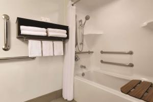 a bathroom with a bath tub and towels at Country Inn & Suites by Radisson, Brooklyn Center, MN in Brooklyn Center