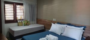 a small room with two beds and a window at Apartamento PIPA - UF01 in Pipa