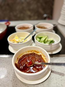 uma tigela de chili e outras tigelas de comida numa mesa em King Park Hotel Kota Kinabalu em Kota Kinabalu