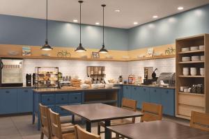 cocina con armarios azules, mesa y sillas en Country Inn & Suites by Radisson, St. Charles, MO, en St. Charles