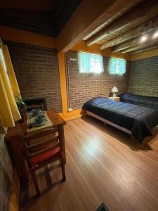 a bedroom with a large bed and a table at Alojamiento ¨El Puente¨ en El Bolsón, para dos personas. in El Bolsón