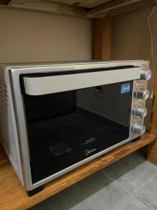 a silver microwave oven sitting on a wooden shelf at Alojamiento ¨El Puente¨ en El Bolsón, para dos personas. in El Bolsón