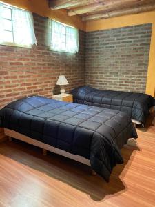 two beds in a room with a brick wall at Alojamiento ¨El Puente¨ en El Bolsón, para dos personas. in El Bolsón