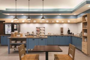 a large kitchen with blue cabinets and a table at Country Inn & Suites by Radisson, Byram/Jackson South, MS in Byram