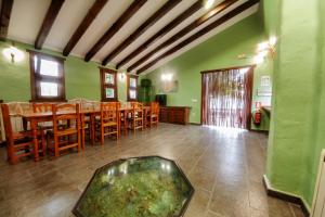 uma sala de jantar com paredes verdes e mesas e cadeiras de madeira em Villarrobles de Altamira em Cortijos Nuevos