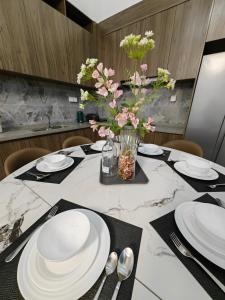 a dining table with white plates and flowers in a vase at Xtu Golf Villa Forest City二房独栋别墅 in Gelang Patah