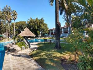 Radisson Hotel Tapatio Guadalajara في غواذالاخارا: منتجع فيه مسبح مع طاولة واشجار