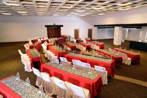 Radisson Hotel Tapatio Guadalajara في غواذالاخارا: قاعة احتفالات بالطاولات الحمراء والكراسي البيضاء
