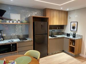uma cozinha com um frigorífico de aço inoxidável e uma mesa em Alto Padrão com Luxo e Conforto nas Alturas em São Paulo