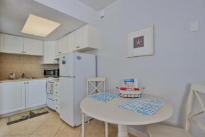 a white kitchen with a table and a white refrigerator at Coastal Waters 106 - A 1-1 Pool Side Retreat in New Smyrna Beach