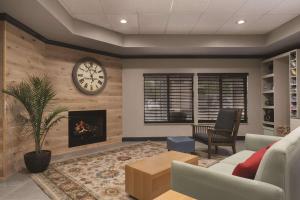 a living room with a fireplace and a clock on the wall at Country Inn & Suites by Radisson, Raleigh-Durham Airport, NC in Morrisville