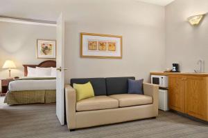 Habitación de hotel con sofá y cama en Country Inn & Suites by Radisson, Charlotte University Place, NC, en Charlotte