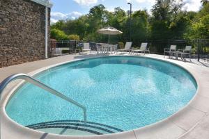 una gran piscina con sillas y sombrilla en Country Inn & Suites by Radisson, Asheville West near Biltmore, en Asheville