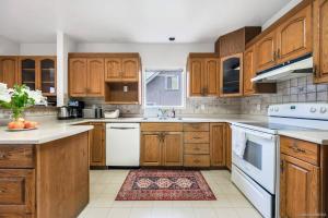 una cucina con armadietti in legno ed elettrodomestici bianchi di Explore Vancouver from Deluxe house with 3 BD a Vancouver