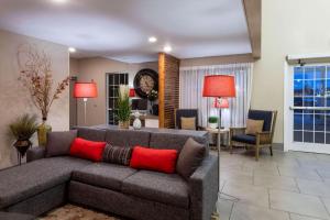 a living room with a gray couch with red pillows at Country Inn & Suites by Radisson, Fargo, ND in Fargo