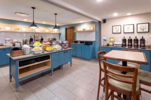 Country Inn & Suites by Radisson, Fargo, ND في فارغو: مطبخ به دواليب زرقاء وطاولة عليها طعام