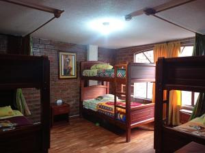 a room with two bunk beds and a brick wall at Hostal D´Mathias in Baños