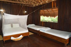 two beds in a room with wooden walls at U-GO Espectacular Casa en Barú con Vistas al Mar in Cartagena de Indias