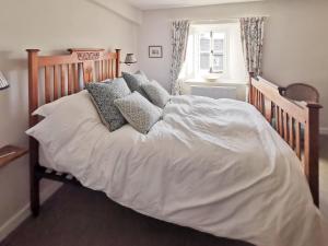 a bed with white sheets and pillows in a bedroom at Earsdon Cottage in Ireby