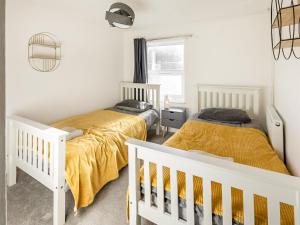 2 camas en un dormitorio con paredes blancas en The Cottage en Gorleston-on-Sea