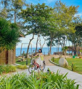 a woman riding a bike down a path near the ocean at Resort Bai Xep Quy Nhon in Quy Nhon