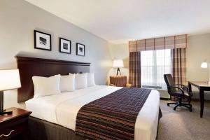Country Inn & Suites by Radisson, Kearney, NE في كيرني: غرفة الفندق بسرير كبير ومكتب