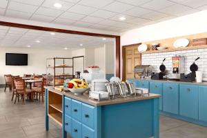 una cocina con armarios azules y una mesa con un bol de fruta en Country Inn & Suites by Radisson, Kearney, NE, en Kearney