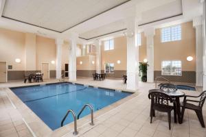 a pool in a large room with a table and chairs at Country Inn & Suites by Radisson, Manchester Airport, NH in Bedford