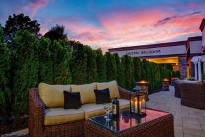 a wicker couch sitting on a patio with a table at Radisson Hotel Freehold in Freehold