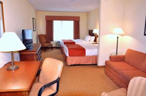 une chambre d'hôtel avec un lit et un canapé dans l'établissement Country Inn & Suites by Radisson, Lake George Queensbury, NY, à Lake George