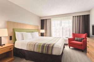 a hotel room with a bed and a red chair at Country Inn & Suites by Radisson, Big Flats (Elmira), NY in Horseheads