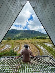 un hombre sentado en un techo mirando a una montaña en A frame Riverston en Matale