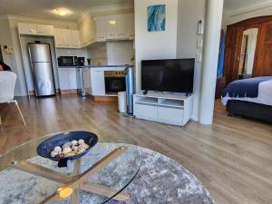 a living room with a flat screen tv and a kitchen at Fairways Golf & Beach Retreat Bribie Island in Woorim