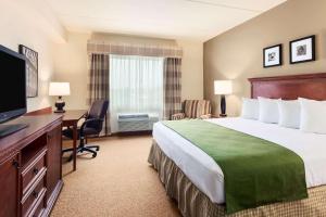 um quarto de hotel com uma cama, uma secretária e uma televisão em Country Inn & Suites by Radisson, Buffalo South I-90, NY em West Seneca