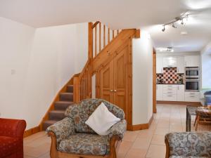 a living room with a chair and a staircase at Sycamore Cottage - Uk45923 in Ballater