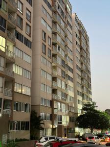 un edificio alto con coches estacionados frente a él en Apartamento cerca a zonas exclusivas de Barranquilla, en Barranquilla