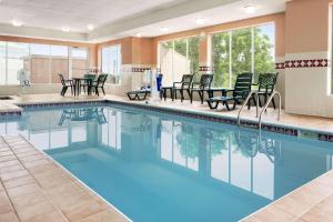 una piscina con sillas y mesas en un edificio en Country Inn & Suites by Radisson, Akron Cuyahoga Falls, en Cuyahoga Falls