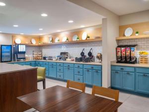 cocina con armarios azules, mesa y sillas en Country Inn & Suites by Radisson, Toledo, OH en Maumee