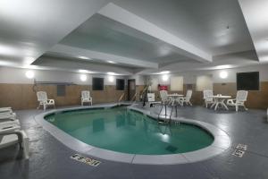 - une grande piscine avec des chaises et des tables dans une chambre dans l'établissement Country Inn & Suites by Radisson, Oklahoma City Airport, OK, à Oklahoma City