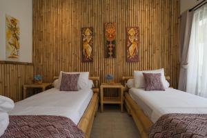 2 łóżka w pokoju z bambusowymi ścianami w obiekcie Tiga Naga Villa w mieście Denpasar