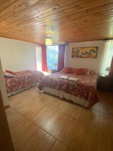 a bedroom with two beds and a wooden ceiling at El Fogon de Rio Claro in Rio Claro