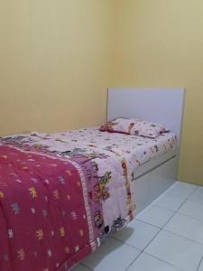 a bedroom with a bed with a pink comforter at Kalibata city apartemen tower akasia in Jakarta