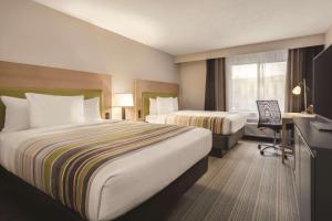 a hotel room with two beds and a desk at Country Inn & Suites by Radisson, Erie, PA in Erie