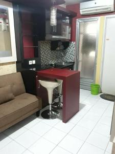 a kitchen with a red counter and a couch at Kalibata city apartemen tower akasia in Jakarta