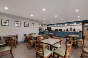 un restaurant avec des tables et des chaises en bois et un comptoir dans l'établissement Country Inn & Suites by Radisson, Harrisburg Northeast - Hershey, à Harrisburg